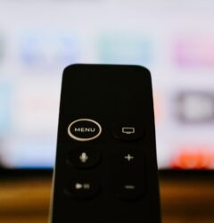 A picture of a black remote control with only 5 buttons on it on a blurred background