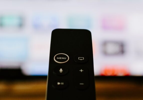 A picture of a black remote control with only 5 buttons on it on a blurred background
