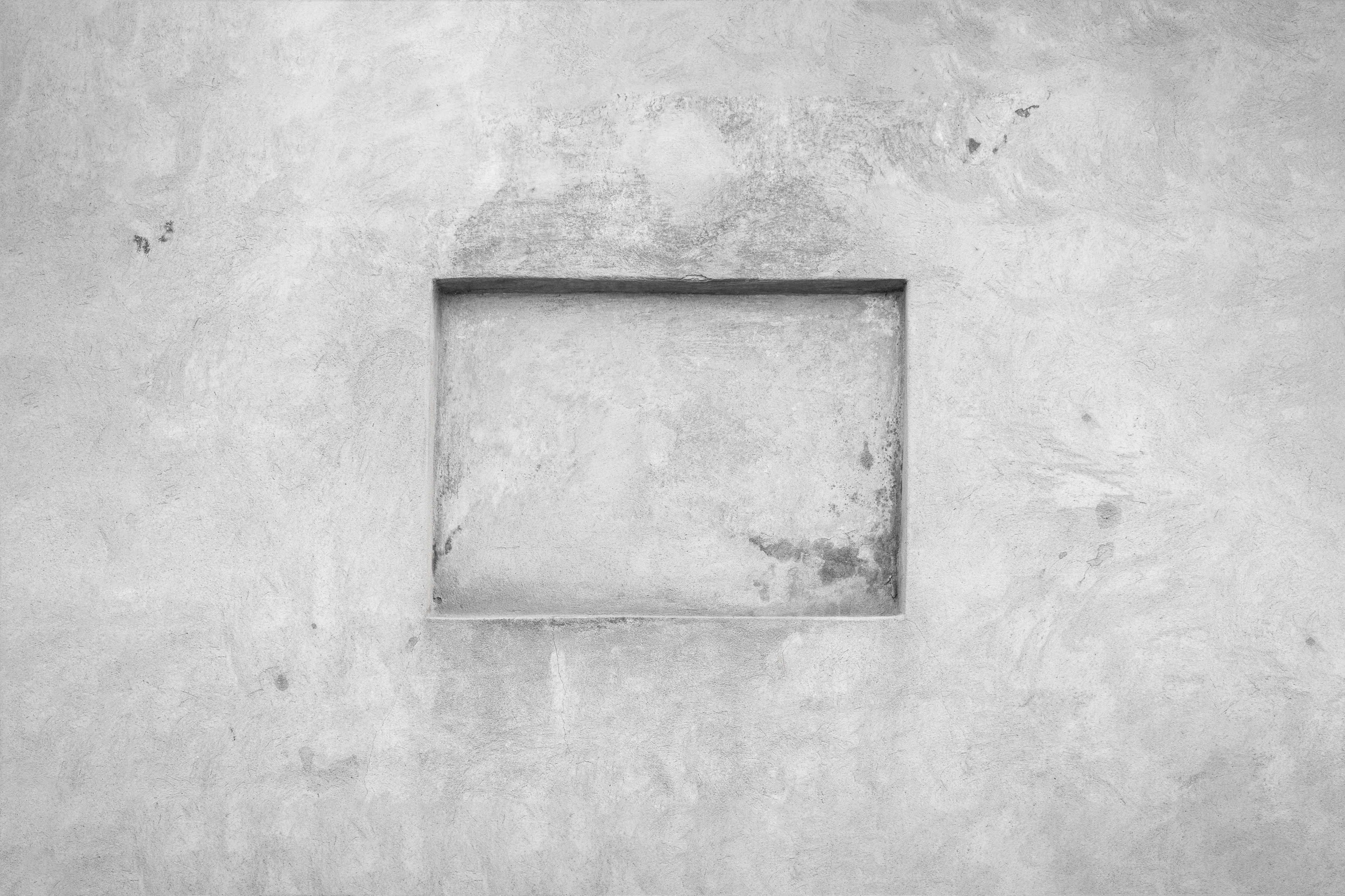 An image of a gray concrete wall with a small, shallow niche in the middle of it